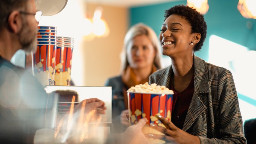 Young female woman buying popcorn at the concession stand while at the movies.