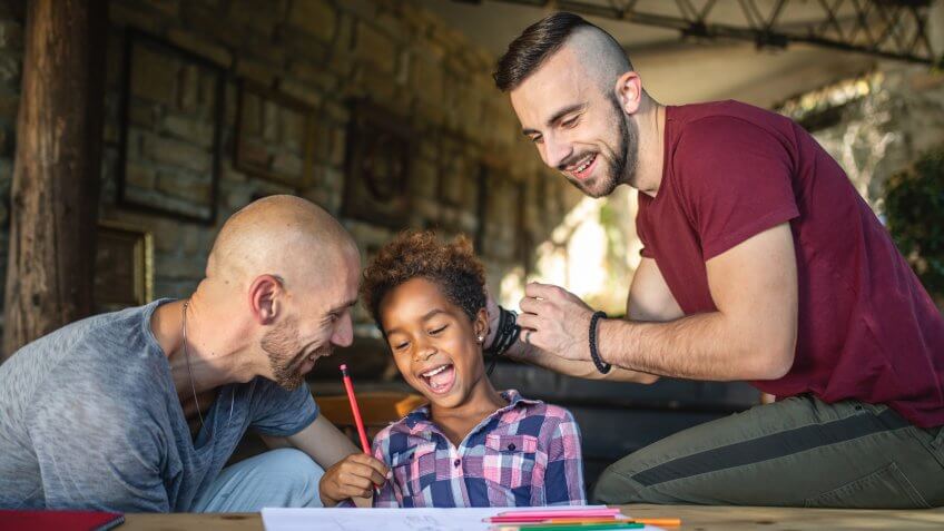 Beautiful and lovely gay homosexual couple enjoying their time spent together as a family with their beautiful adopted mixed race daughter.