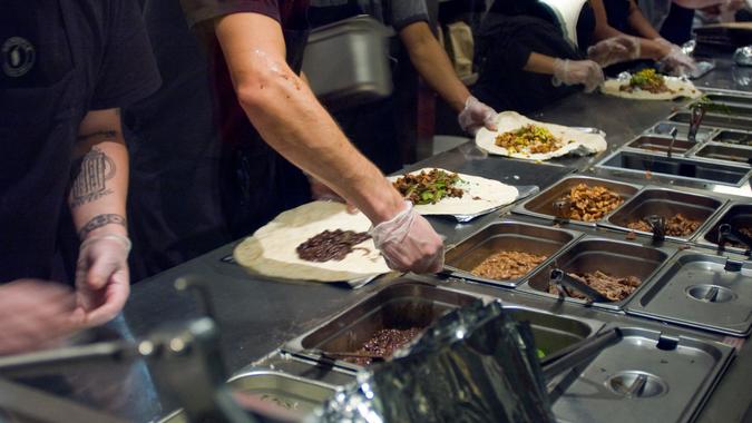 Chipotle workers make burritos for customers
