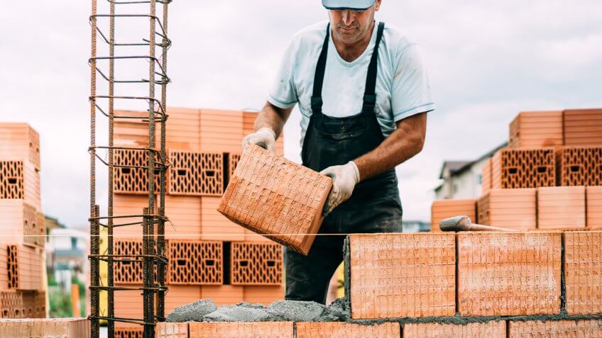 professional, portrait of industrial worker building walls with ceramic bricks.