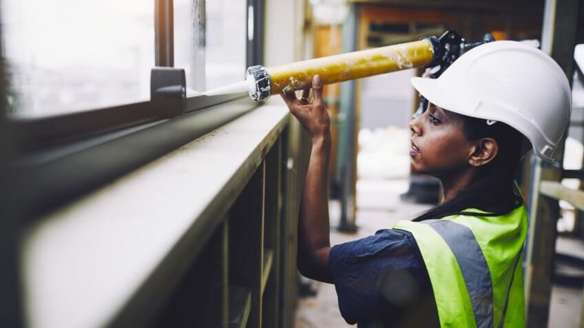 construction worker applying glue to a sill