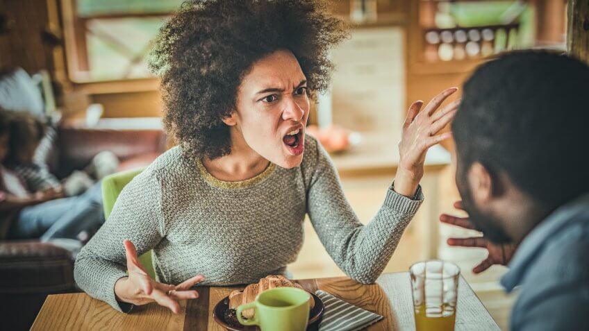 Young black couple arguing while having problems in their relationship at dining table.
