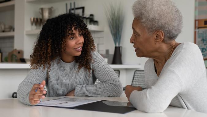 An ethnic female financial consultant is discussing strategy with an elder senior woman.