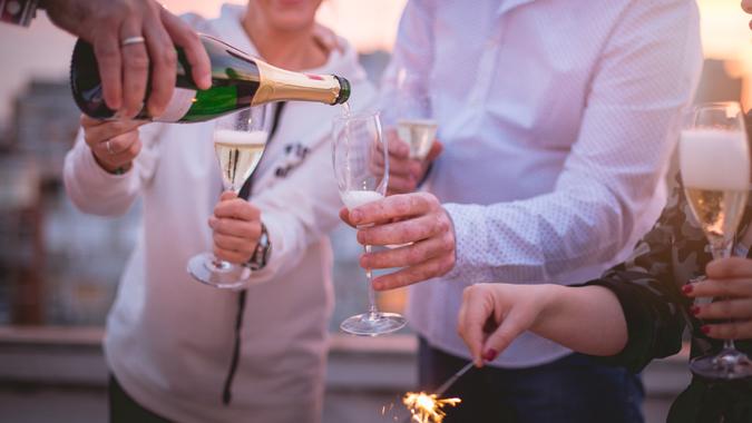 Pouring champagne Close up of a group of four friends is on a roof top of a building, celebrating with champagne and sparklers.