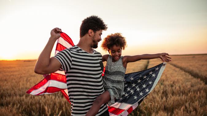 Father and daughter holding American flag.