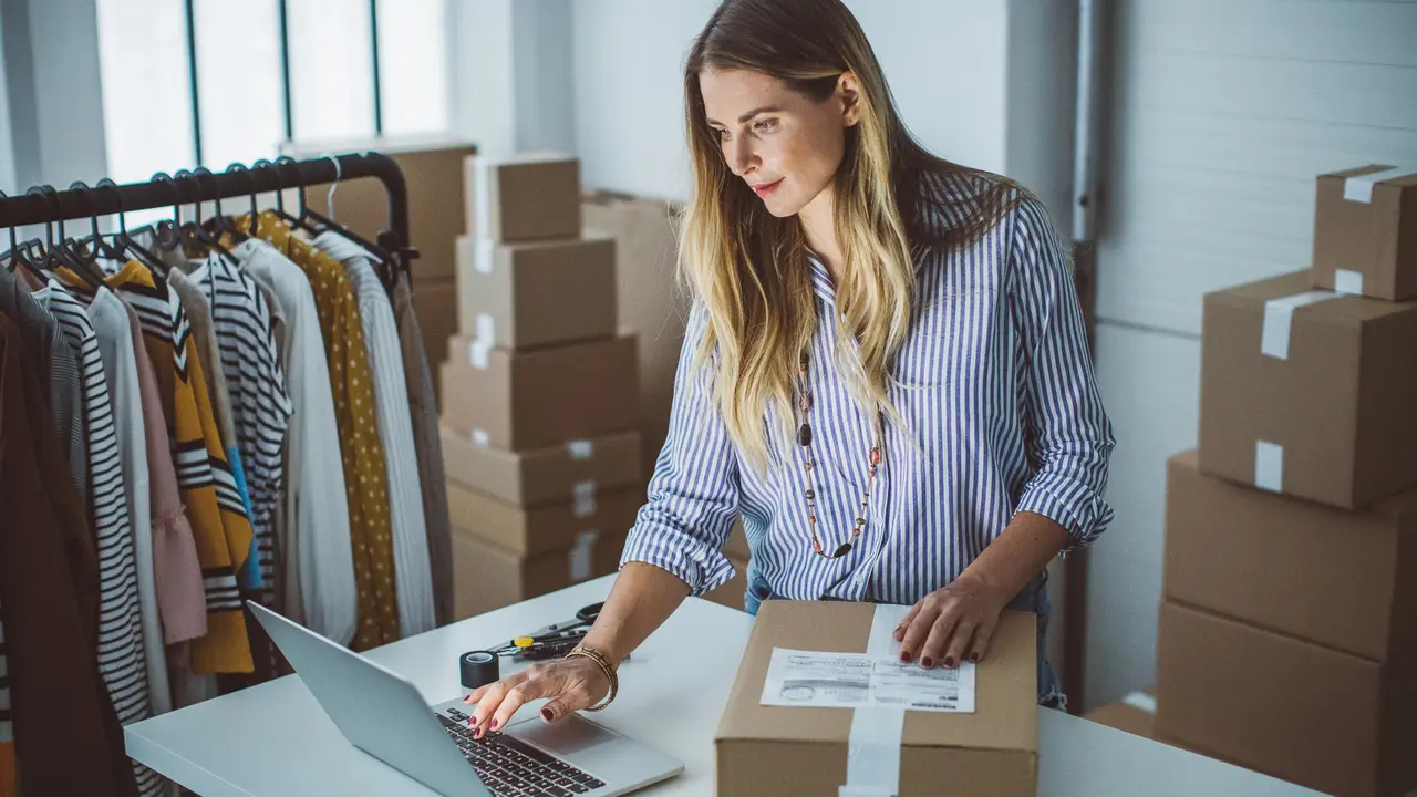 Women, owener of small business packing product in boxes, preparing it for delivery.