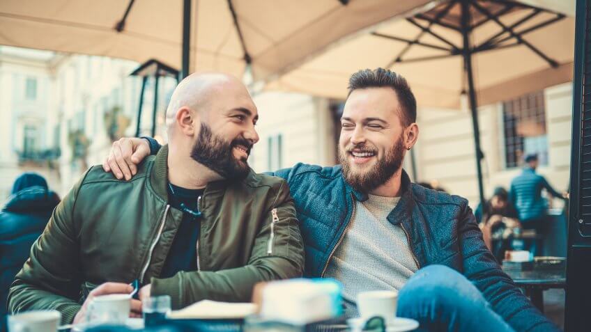 Two Smiling Handsome Friend Drinking Coffee and Talking at Favorite Coffee Place.