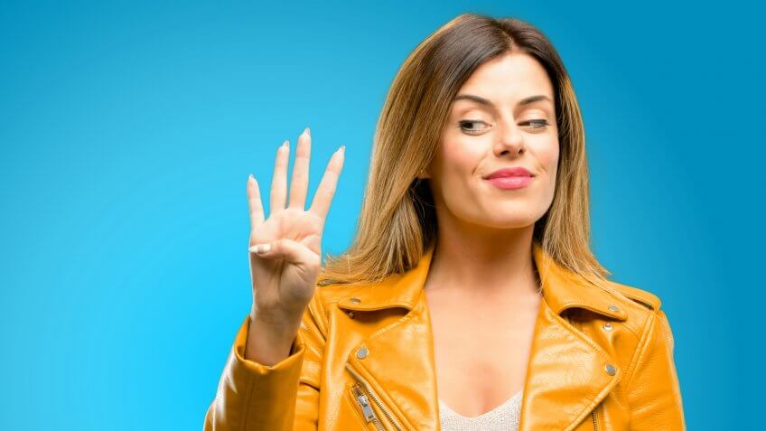 Beautiful young woman raising his finger, is the number four, blue background - Image.