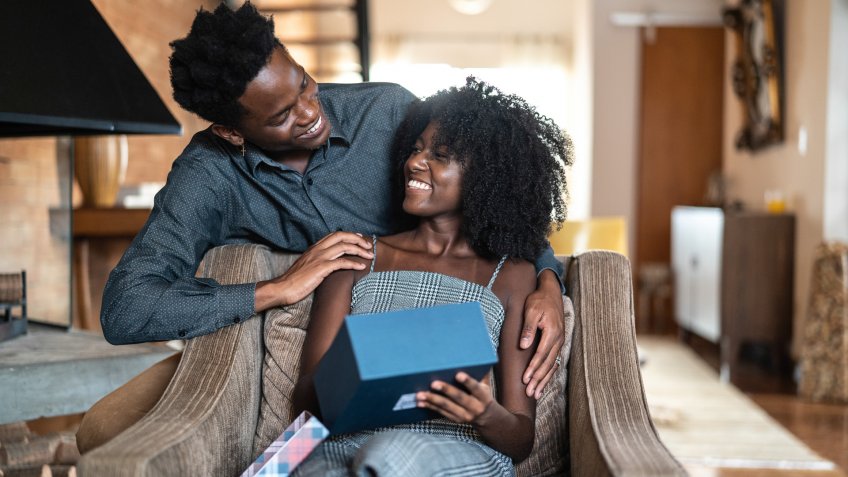 African descent brazilian couple exchanging gifts at home.