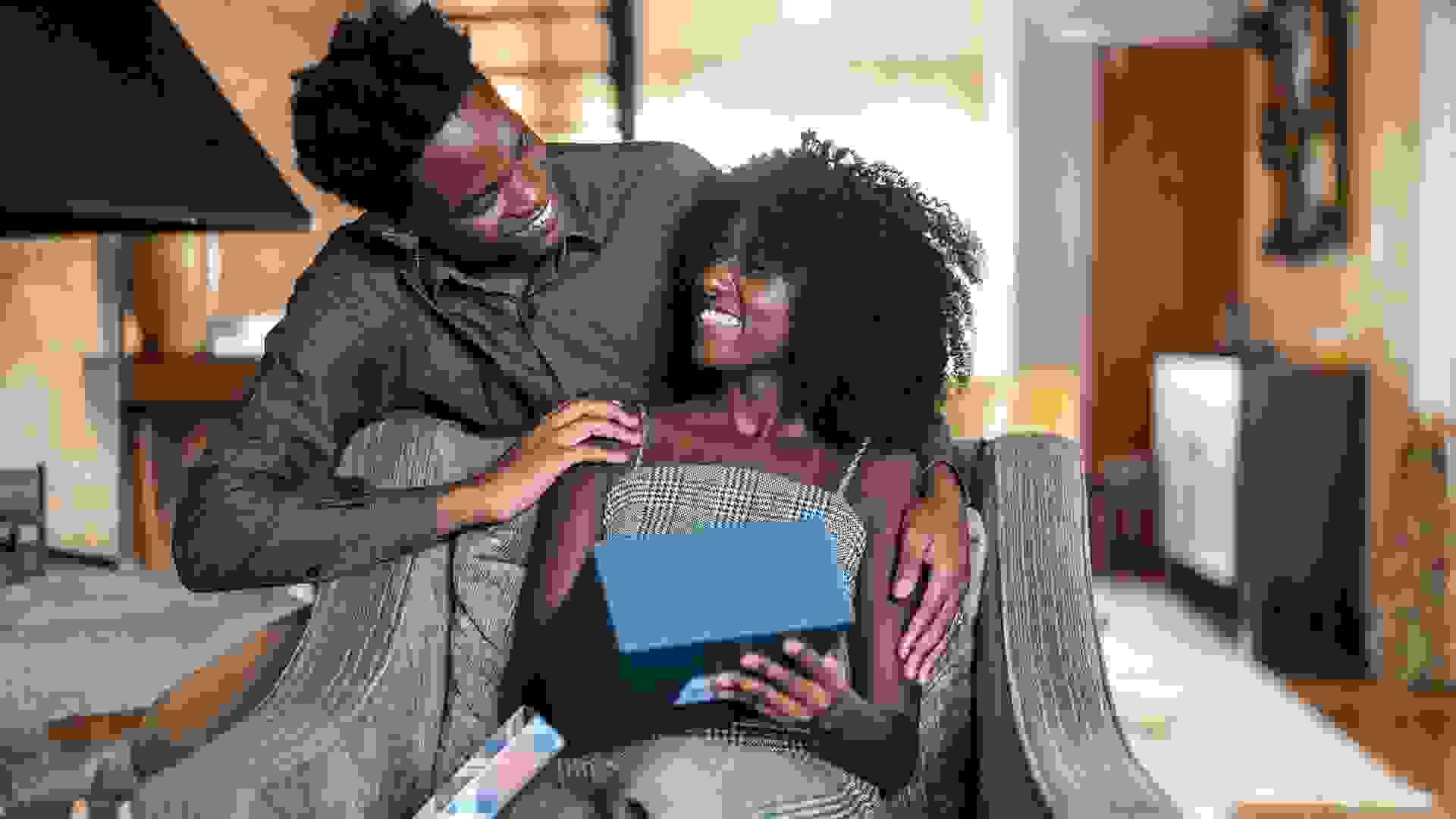 African descent brazilian couple exchanging gifts at home.