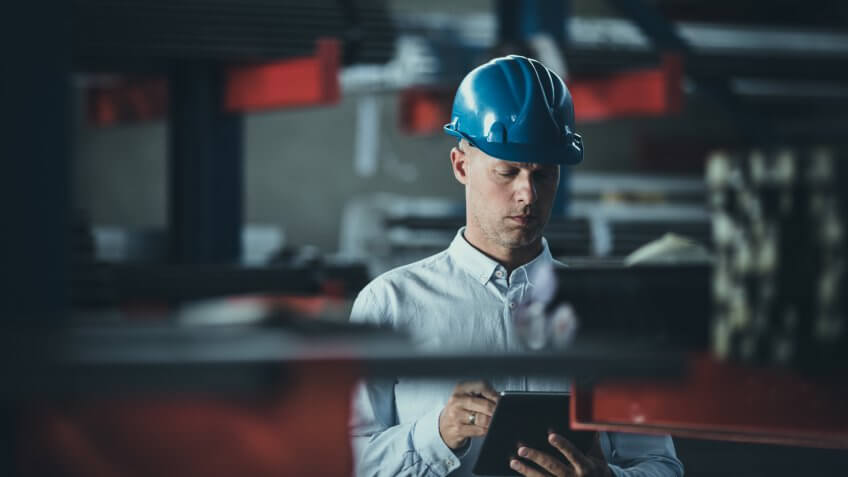 Male manager reading a plan on a touchpad while being in a warehouse.