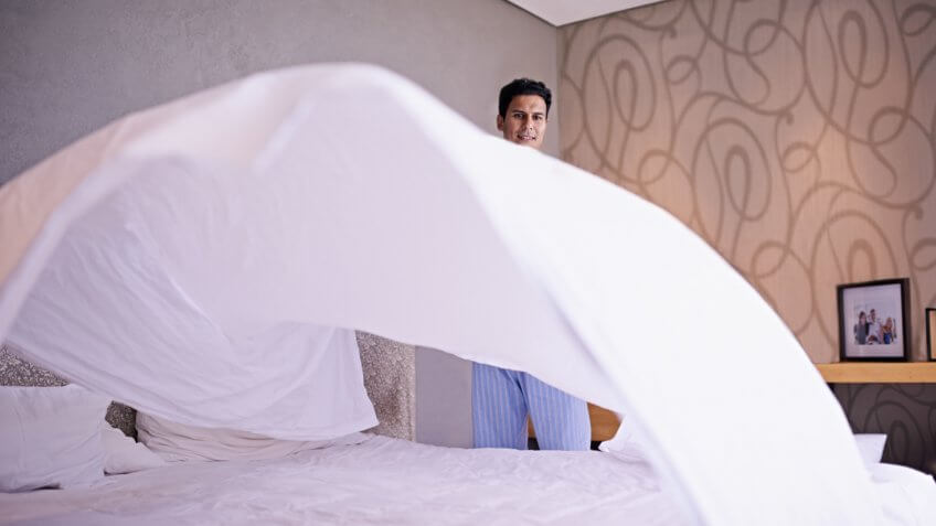 Shot of a young man making his bed in the morninghttp://195.