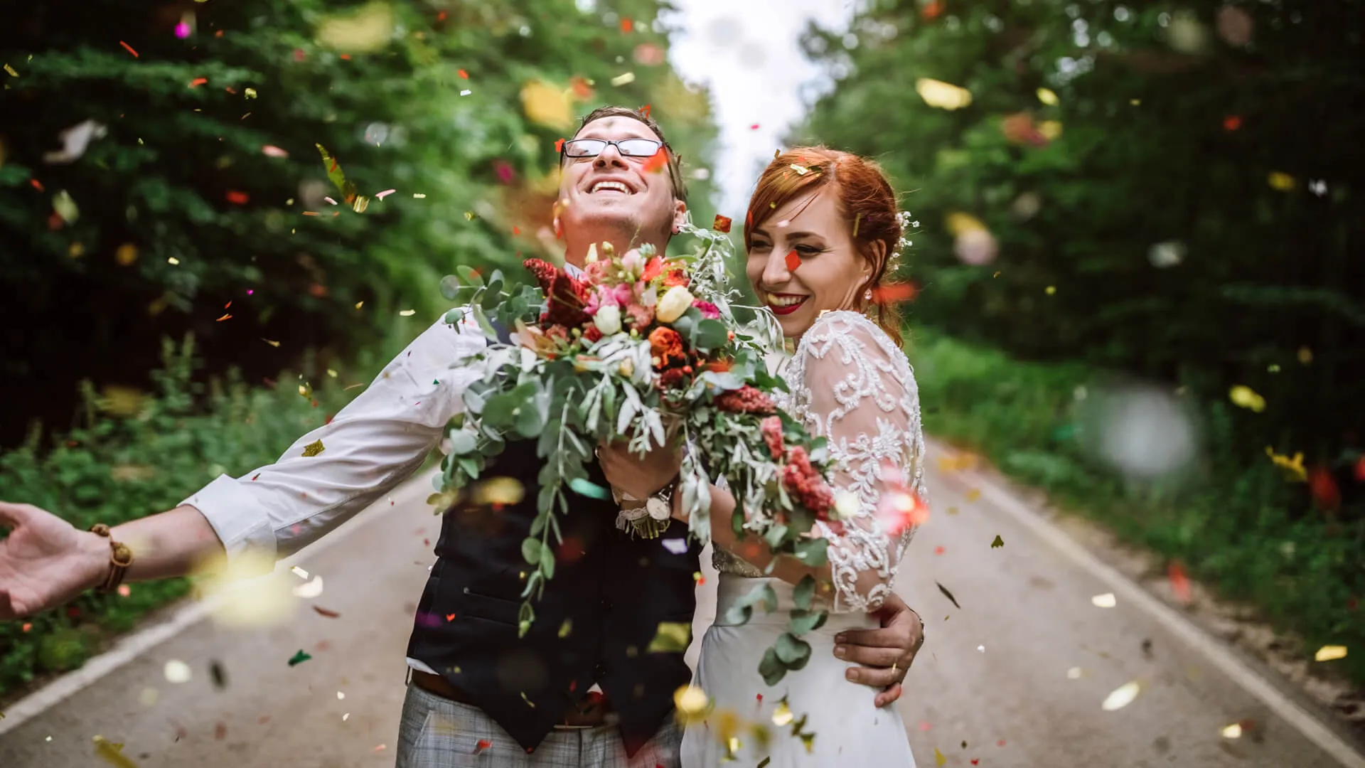 年轻漂亮的新婚夫妇微笑着向他们的婚姻投掷五彩纸屑和欢呼。