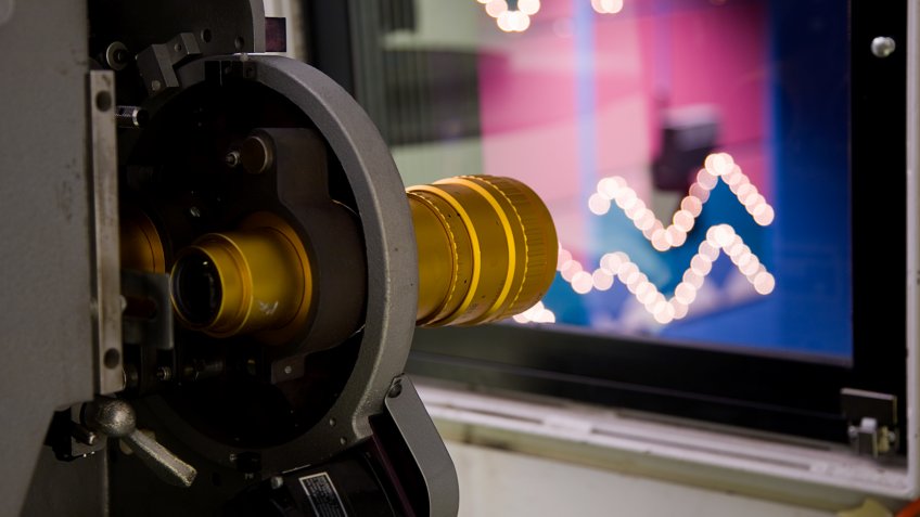 A movie projector in the projectionist booth of a movie theater.