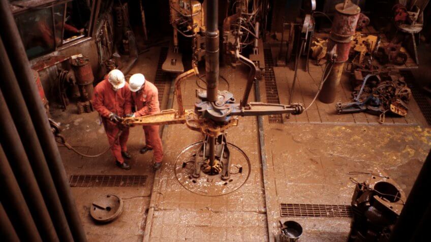 two roustabouts working on oil rig platform drill floor