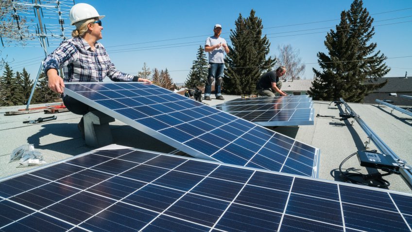 Workers installing solar panels on a residential homes roof.