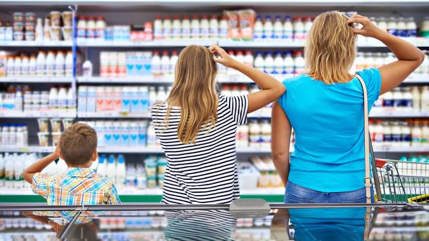 Mother and children are choosing dairy products in shop.