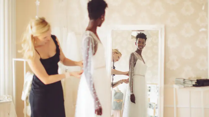 Fashion designer is adjusting the wedding dress.