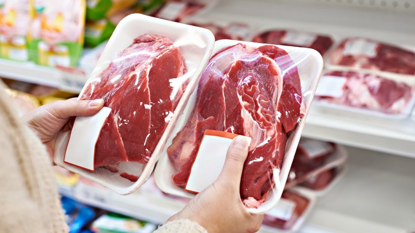 Buyer hands with beef meat packages at the grocery store.