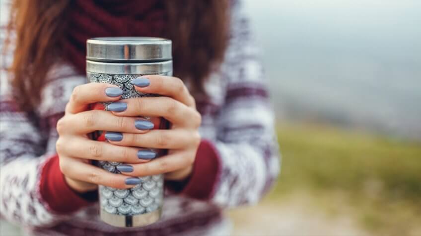 Young woman holding warm cup of tea.
