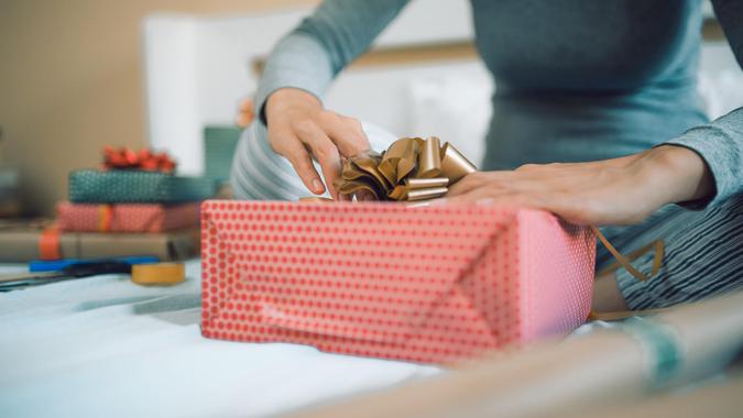 Young woman in her bedroom, wrapping Christmas gifts.