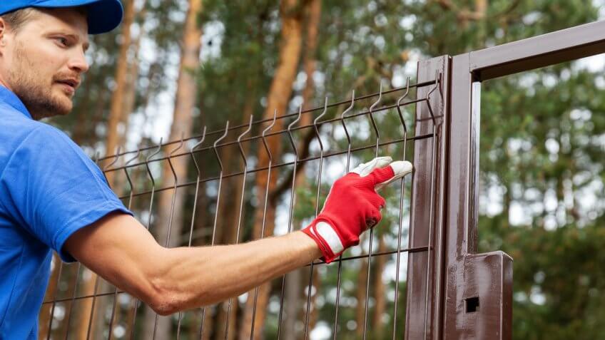 territory enclosure - worker installing metal fence.