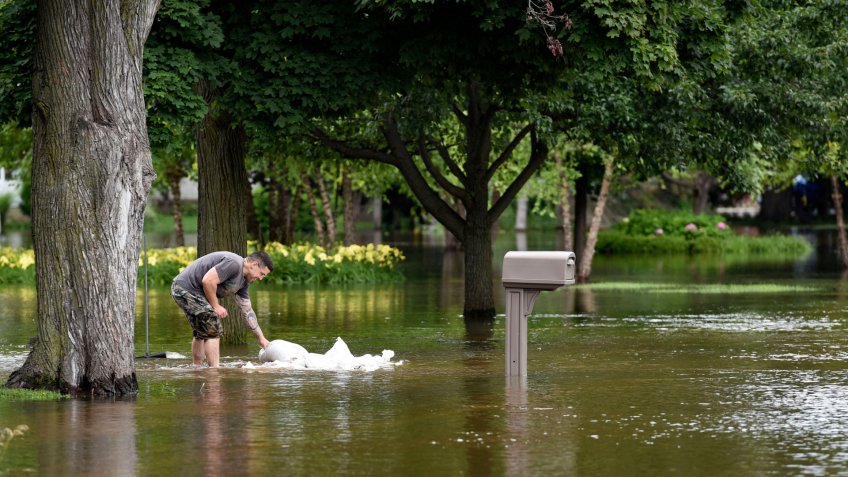 Mandatory Credit: Photo by AP/Shutterstock (8961619a)A man picks up sandbags to reinforce the barrier he build to keep the flood water from reaching his house, in Gurnee, Ill.