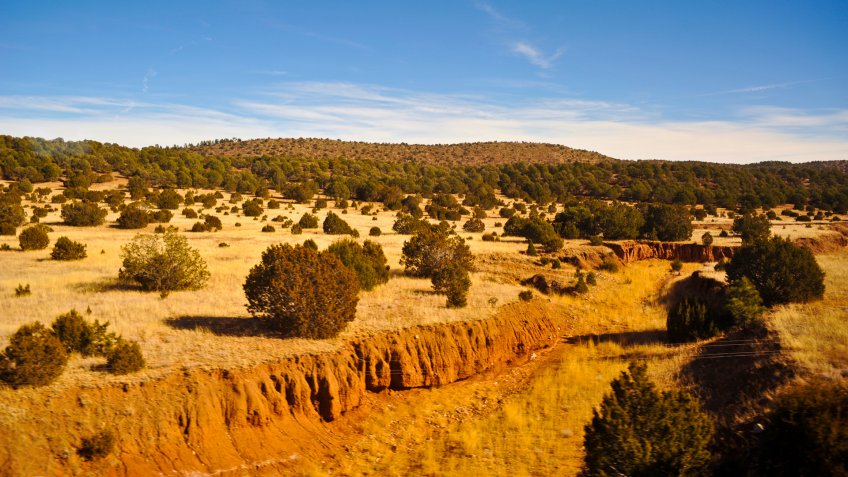 LAS VEGAS, NM / USA - DECEMBER 10 2010: Red soil makes up the steep bank of an arroyo in New Mexico about 10 miles northeast of Las Vegas, New Mexico, looking south from Amtrak Southwest Chief train.