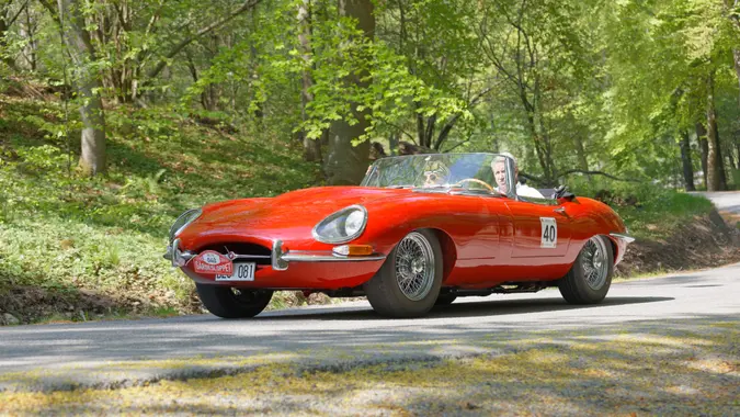 STOCKHOLM, SWEDEN - MAY 22, 2017: Red Jaguar E-Type classic car from 1965 driving on a country road in the public race Gardesloppet in the forests at Djurgarden, Stockholm, Sweden.