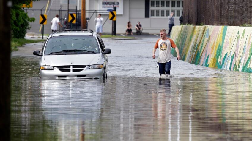 Mandatory Credit: Photo by Michael Conroy/AP/Shutterstock (6244417a)A pedestrian walks past a stranded vehicle caught in rising flood waters after heavy rain fell in IndianapolisIndiana Storms, Indianapolis, USA.