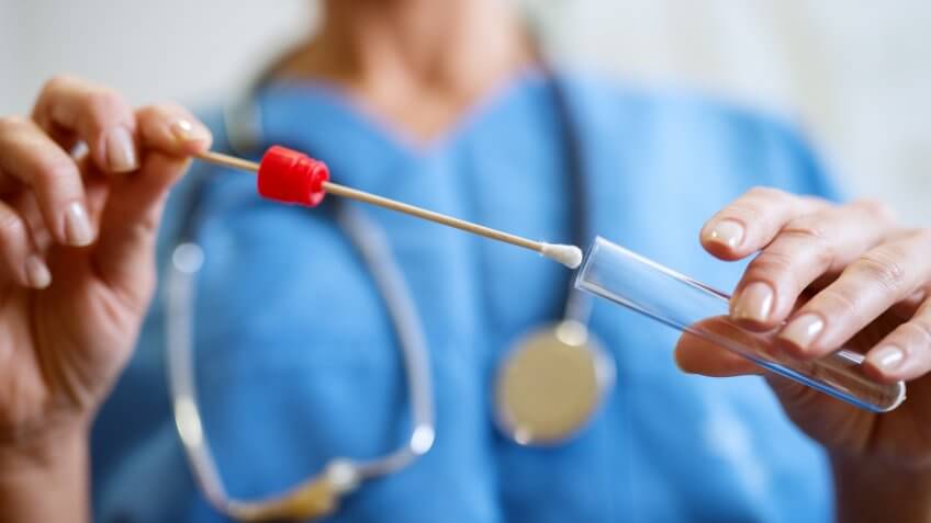 Close up of nurses hands holding buccal cotton swab and test tube ready to collect DNA from the cells.