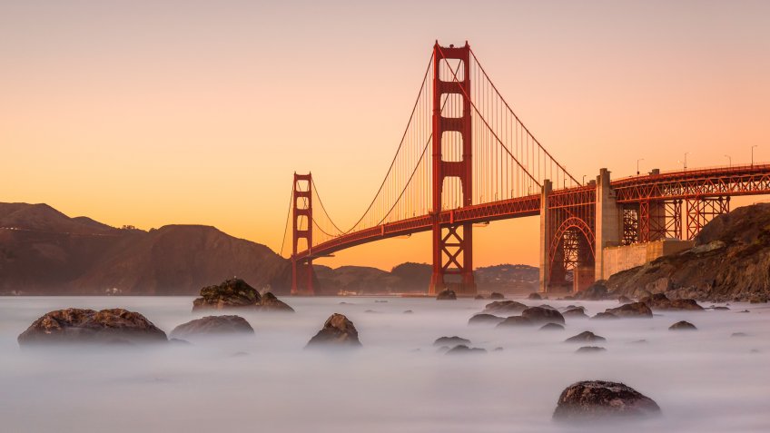 Long exposure photo in Marshall's Beach with Golden Gate Bridge in the background in San Francisco at sunset, California.