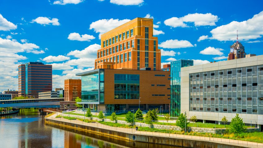 Downtown Lansing skyline buildings with Grand River and building reflections.