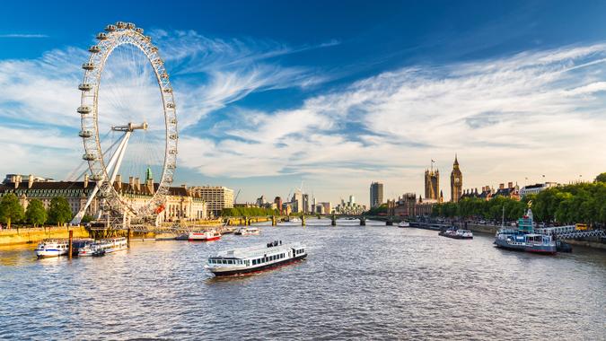 LONDON, JULY 2017 - View of Westminster Parliament, Big Ben and London Eye with Thames and tourist ship in foreground on a sunny summer afternoon.