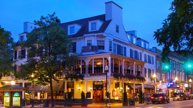 College Avenue with stores and restaurants in downtown State College, Pennsylvania illuminated in the evening.