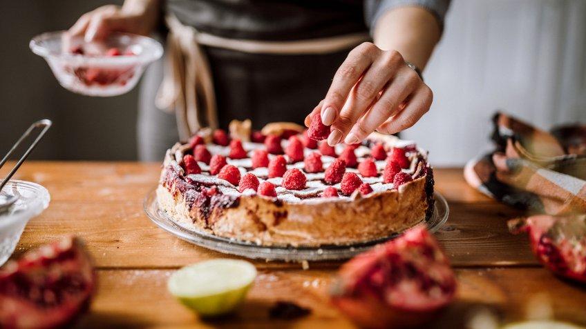 Woman Putting Raspberries To American Blackberry Pie, While It Is In Mold.