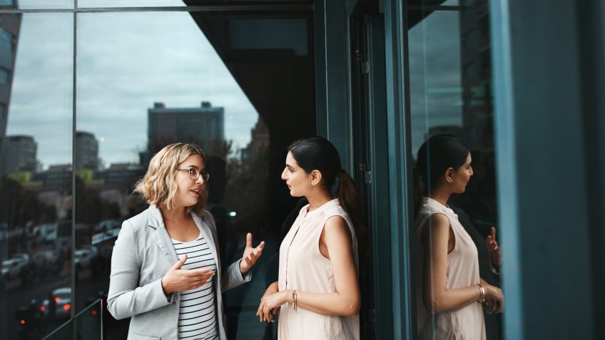 Shot of two businesswomen having a discussion on the office balcony.
