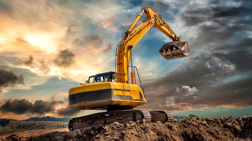 Crawler excavator during earthmoving works on construction site at dawn.