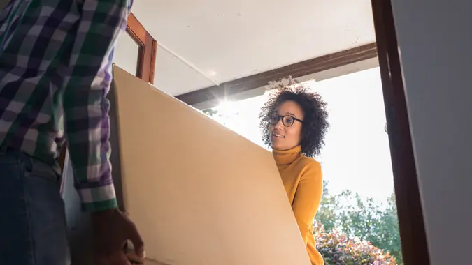 Close up back lit low angle young couple moving boxes into new home.