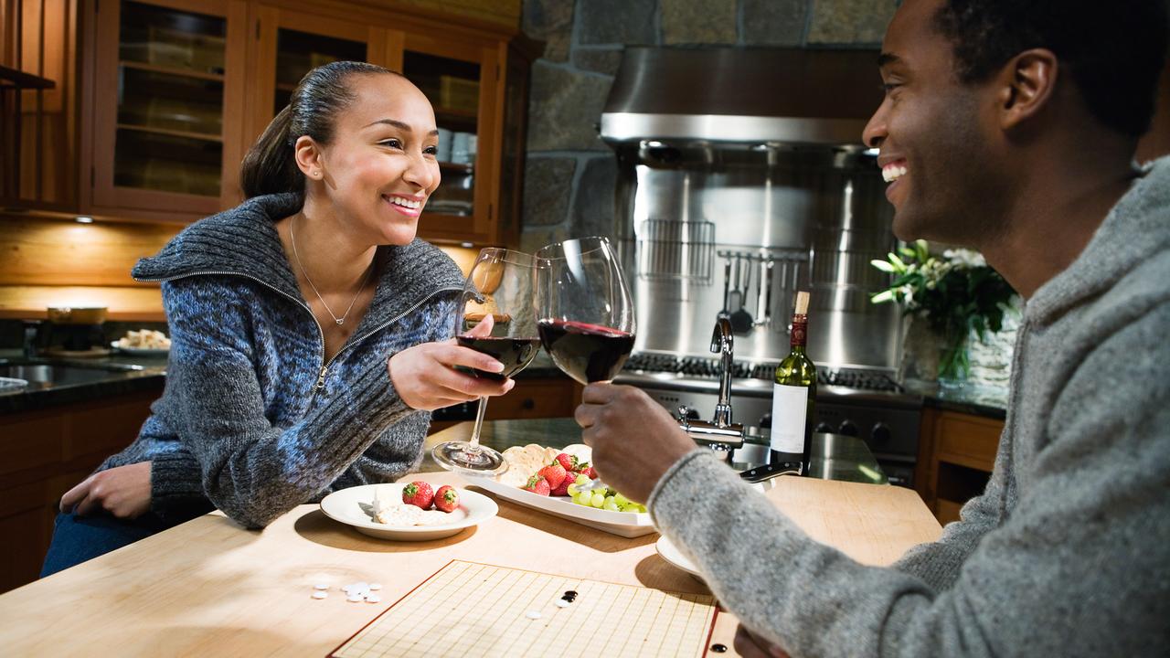 Canada, Cheese, Face To Face, Fruit, Happiness, Heterosexual Couple, Holding, Horizontal, Indoors, Male, Mid Adult, Photography, Plate, Playing, Red Wine, Sitting, Ski Resort, Smiling, Togetherness, Two People, Winter, african, board game, color, evening, female, house interior, kitchen, man, mid adult man, mid adult woman, mixed race ethnicity, toasting, wine glass, woman
