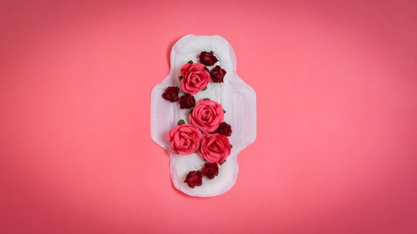 White sanitary pad with red and pink flowers on it, woman health or body positive concept.