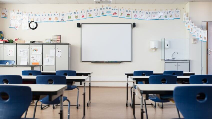 School desk and chairs in empty modern classroom.