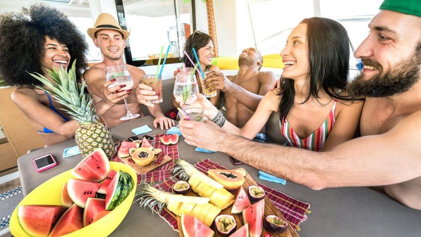 Happy friends drinking fancy cocktails at boat party trip - Young millenial people having fun on luxury vacation - Travel lifestyle concept with millennials sharing aperitif drinks with tropical fruit - Image.