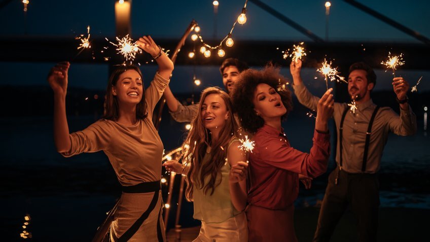 Group of friends holding sprinklers on a boat cruise.