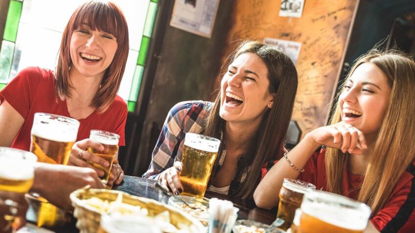 Happy girlfriends women group drinking beer at brewery bar restaurant - Friendship concept with young female friends enjoying time and having genuine fun at cool vintage pub - Focus on left girl.
