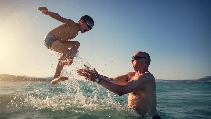 Little boy playing with his grandfather in the sea.