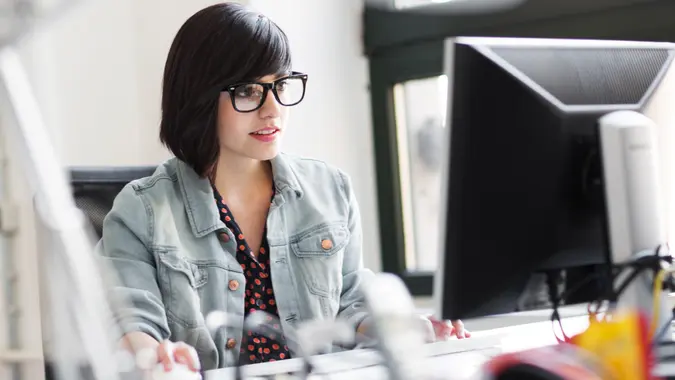 Young hispanic businesswoman working in a modern loft space on a desk.