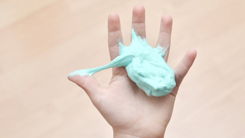 Closeup of an 8 year old boy with sticky putty in his hand.