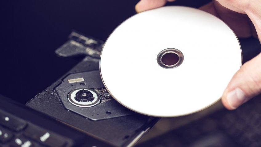 Male hand inserting a DVD into a disk drive.