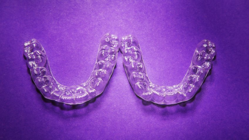 Isolated transparent teeth prosthesis over purple for design.